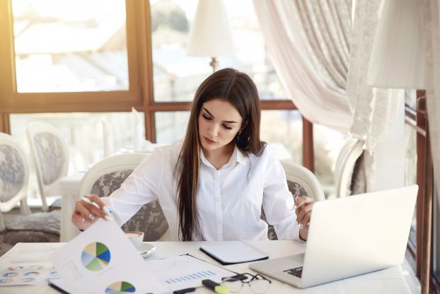 a woman analyzing documents while attending an online meeting.