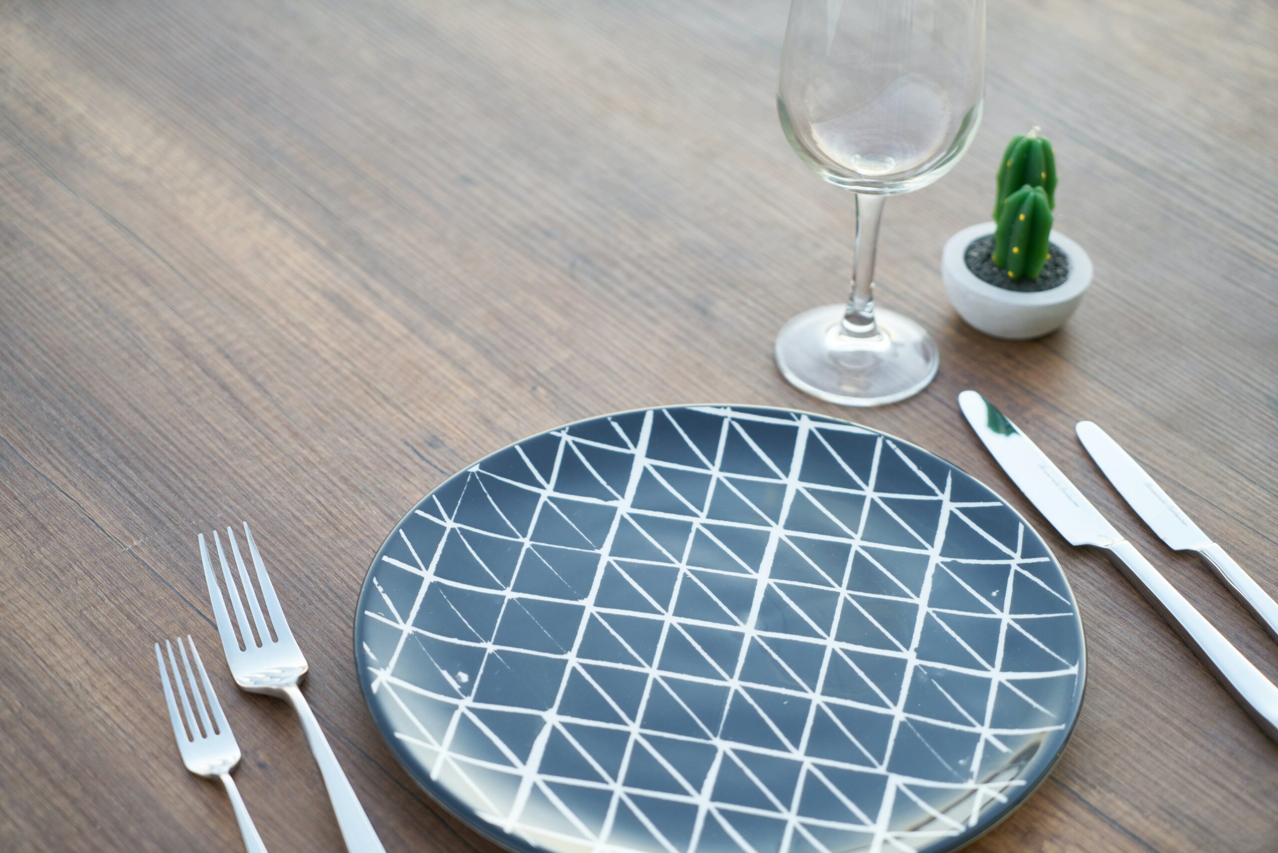 round blue and white ceramic plate two forks two knives and a wine glass