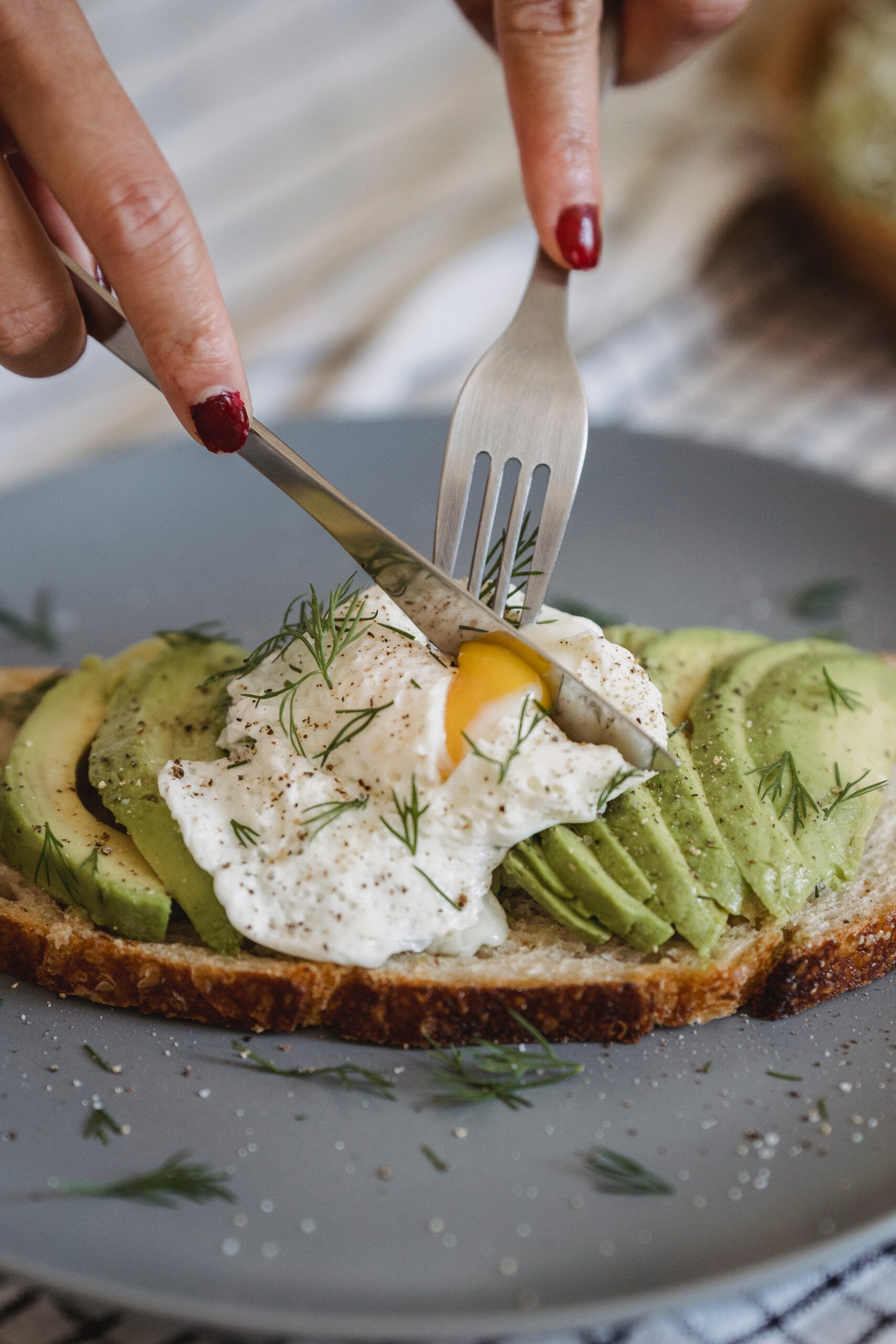 sliced poached egg on top of toasted bread with green fresh fruit and rosemary 