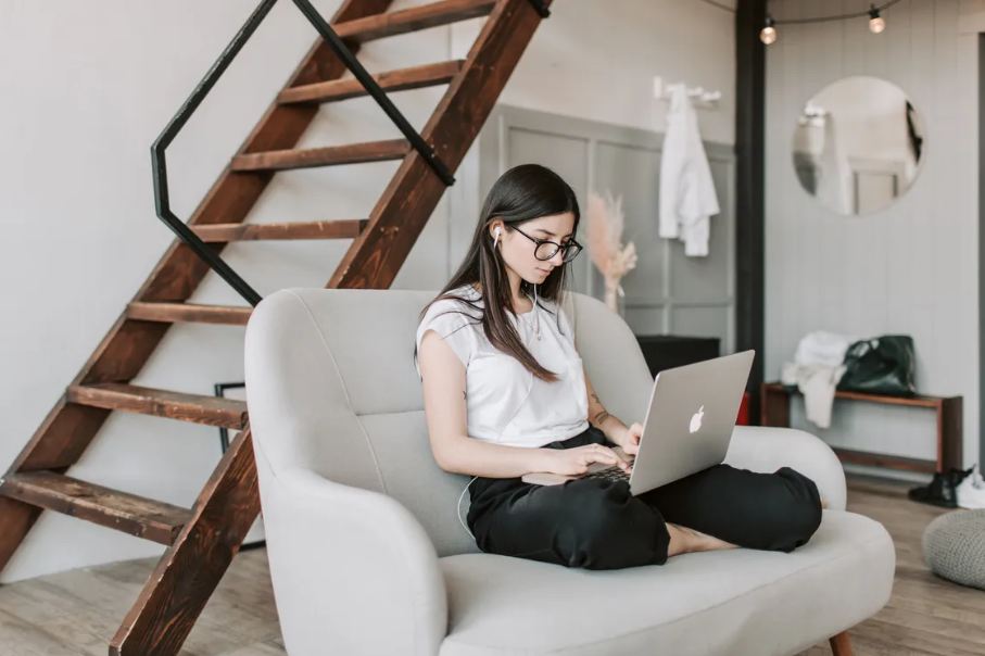 A Woman with Earphones using Laptop at home during work