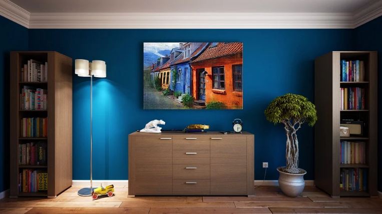 a painting hangs on a blue wall, there is a cardboard floor, and cabinets and drawers