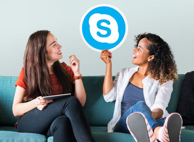 An image of two young women sitting on the sofa with a skype icon.