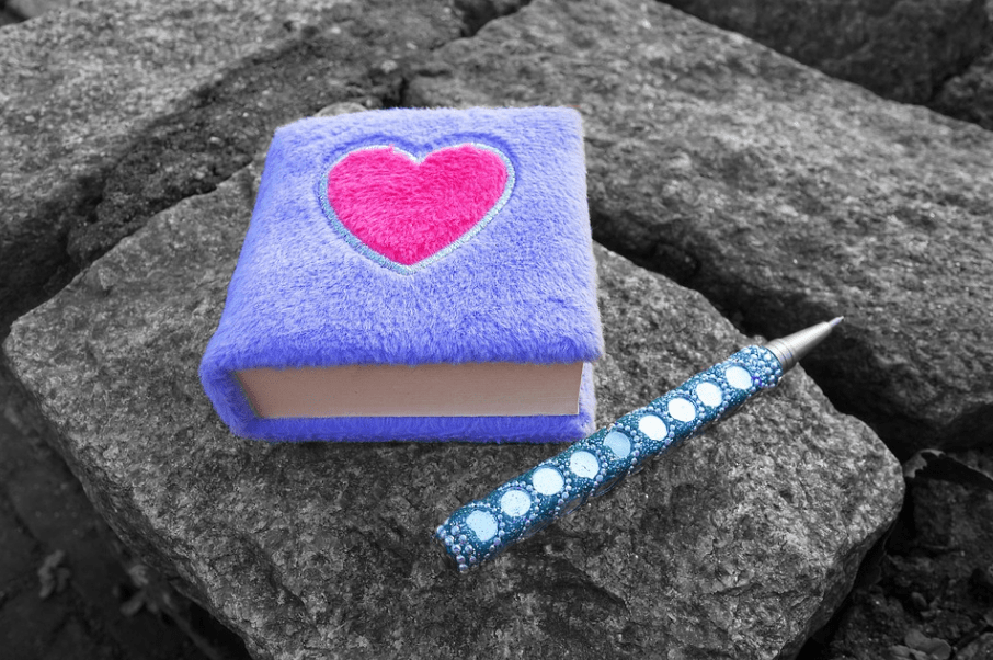 a blue, fluffy diary with a pink heart at the center and a blue pen on the right