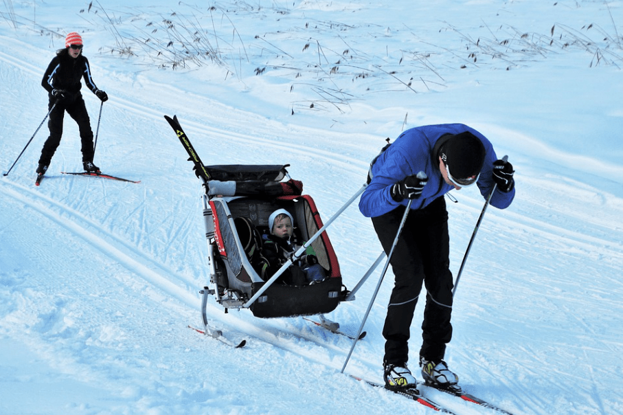 a father skiing with his child, the mother follows behind