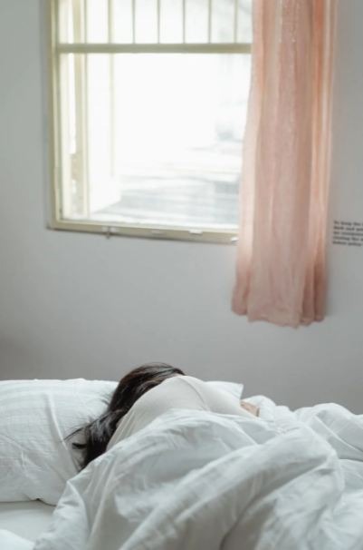 woman-lying-on-bed-near-window