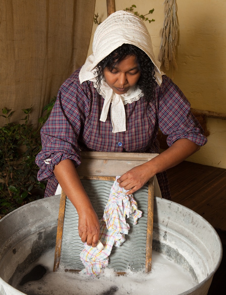 a woman washing laundry with an antique washboard