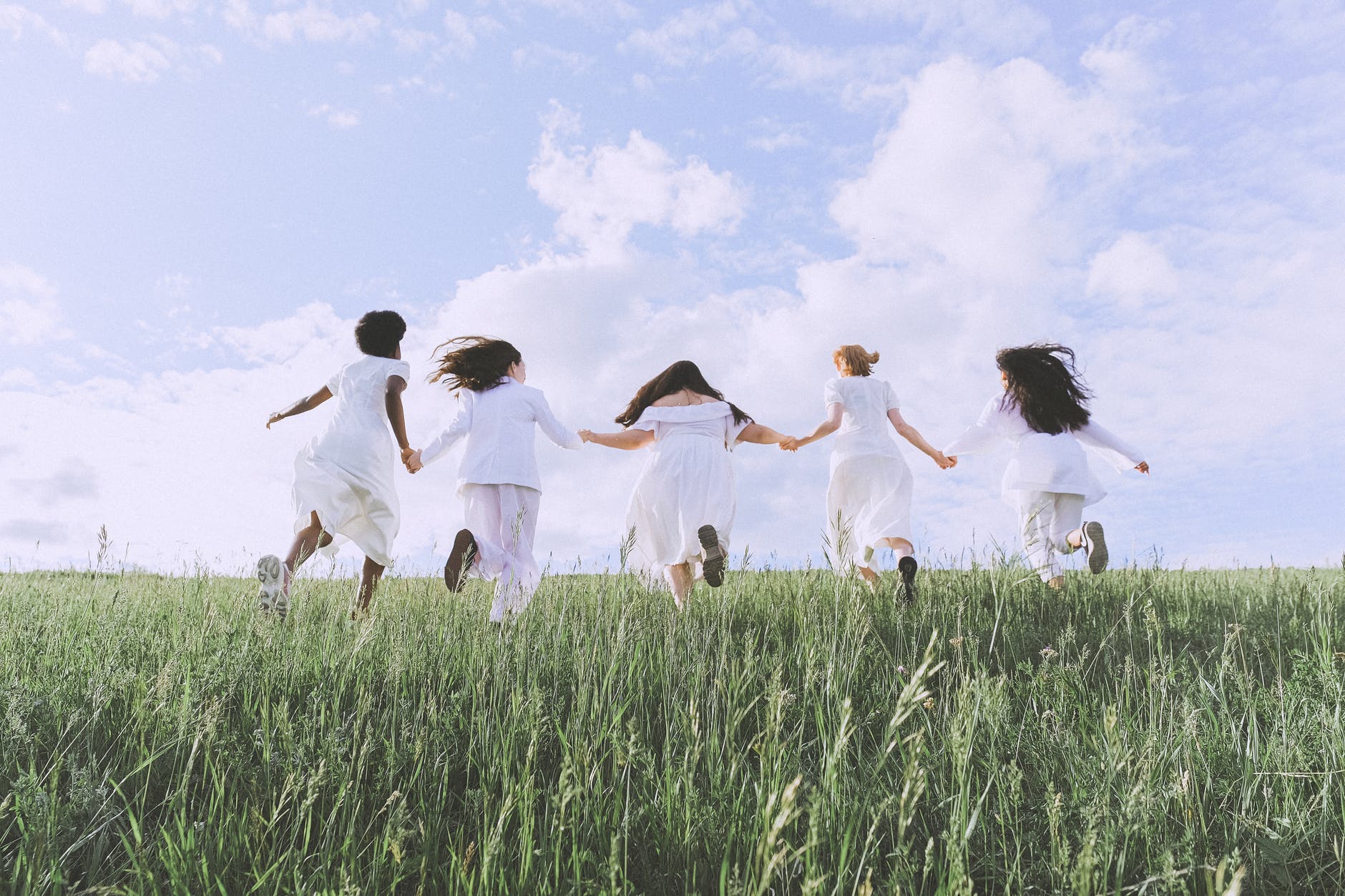 five women wearing white clothes, women running, grass field