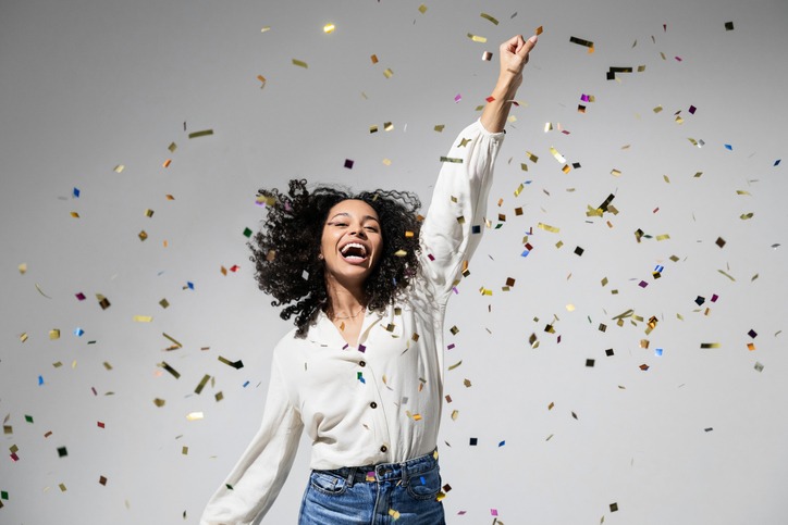 Beautiful excited woman at celebration party with falling confetti