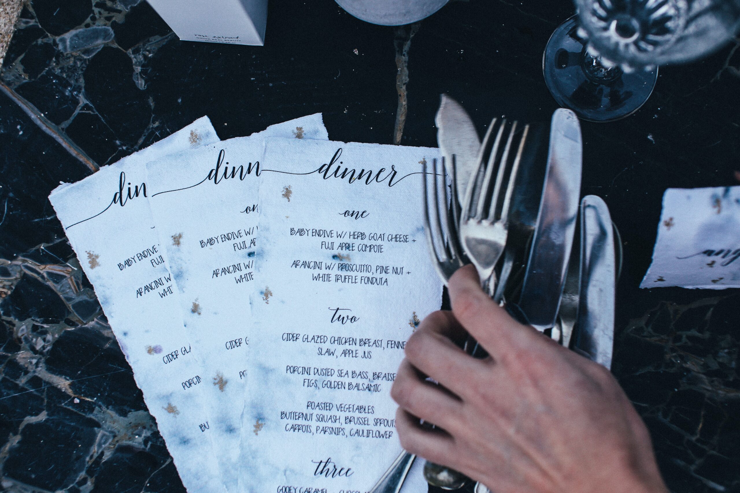 dinner menus and a man grabbing a bunch of cutlery